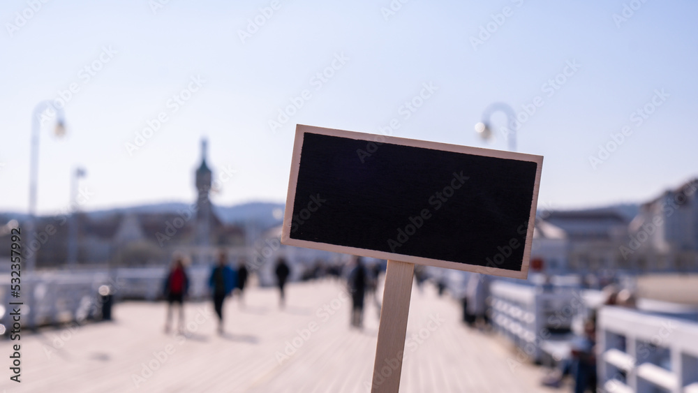 Obraz premium Blank Black billboard against Crowds of tourists The Sopot Pier in the city on the Baltic Sea. Empty mockup template Visitors walking The pier is the longest wooden pier in Europe. Blackboard label