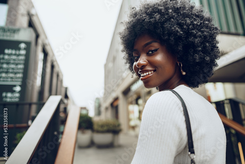 Young smiling african woman poses near stairs in the city photo