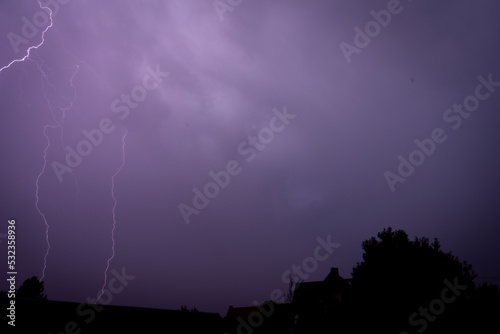 Lightning strikes painting the sky purple on a summer evening during a thunderstorm view from a window