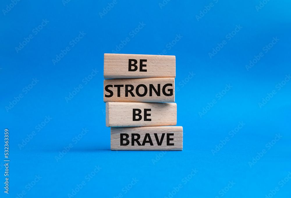 Be strong be brave symbol. Concept words Be strong be brave on wooden blocks. Beautiful blue background. Business concept. Copy space. Be strong be brave symbol. Concept words Be strong be brave on wooden blocks. Beautiful blue background. Business concept. Copy space.