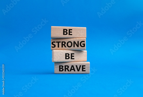 Be strong be brave symbol. Concept words Be strong be brave on wooden blocks. Beautiful blue background. Business concept. Copy space.