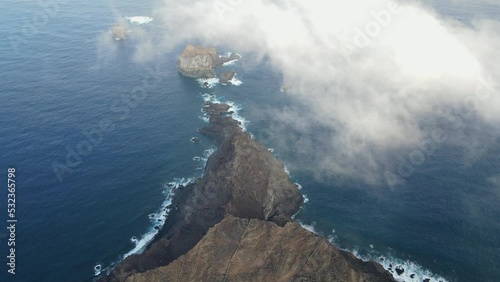 aerial shot between the clouds and the mountains, revealing the Roque de Salmor, on the island of El Hierro, in the Canary Islands. Spain. photo