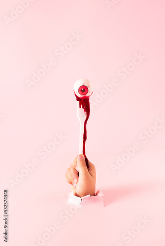 Blood from the eyeball drips down the hand. Creative scary Halloween concept.