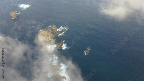 aerial shot between the clouds and revealing the Roque de Salmor, on the island of El Hierro, in the Canary Islands. Spain. photo