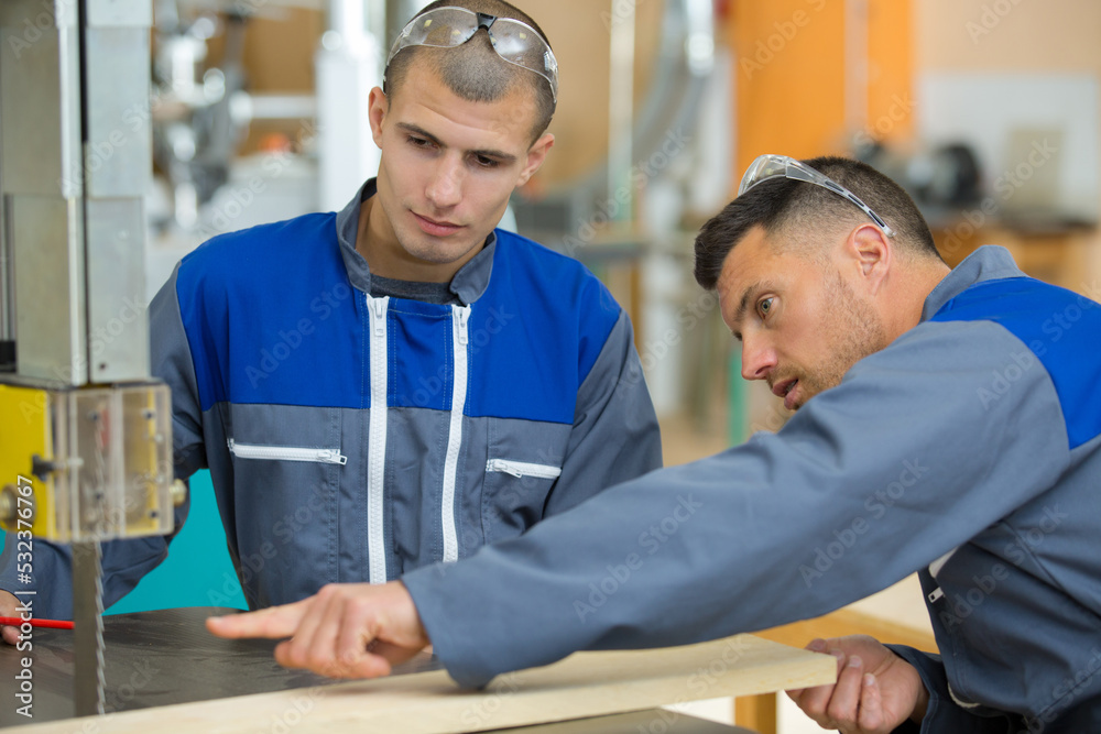 Obraz premium two men builder with circular saw having a conversation