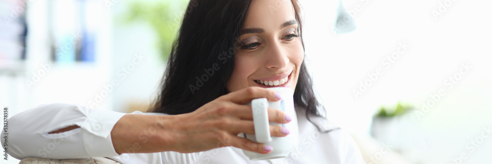 Young woman drinks from cup while sitting on couch Young woman drinks from cup while sitting on couch