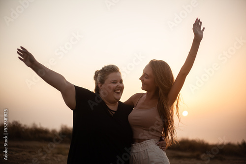 group of friends, plus size with  thin girl spend happy time together and posing in the nature. Beautiful overweight and strong women have fun, enjoy the momet of sunset . photo