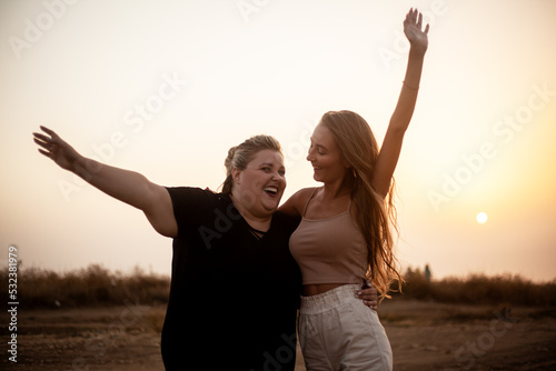 group of friends, plus size with  thin girl spend happy time together and posing in the nature. Beautiful overweight and strong women have fun, enjoy the momet of sunset . photo