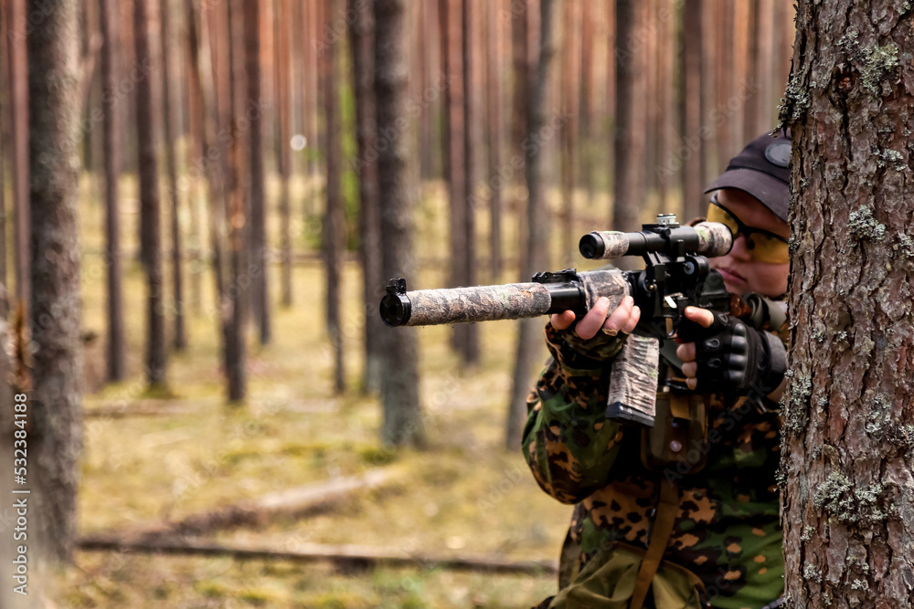 Russian soldier sniper man dressed military disguise camouflage uniform with rifle in woodland at nature background, looking. Male border guard in country border weapon with on war. Copy text space