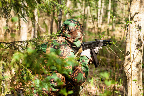 Russian soldier man dressed military camouflage uniform with weapon in woodland at nature background, rear view. Male border guard in country border with autogun on war. Copy text space
