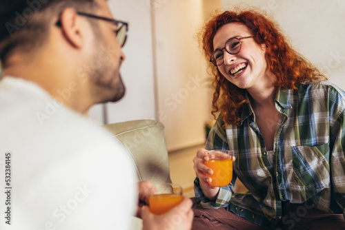 Happy young couple enjoying fresh orange juice for a breakfast at home