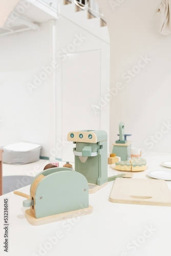 Pastel colorful toy kitchen with wooden kitchen utensils ready for children play. Stylish kid s playing room interior for toddlers