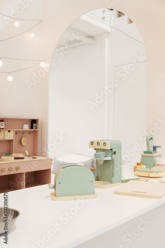 Pastel colorful toy kitchen with wooden kitchen utensils ready for children play. Stylish kid's playing room interior for toddlers
