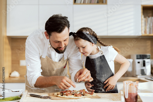 Bild auf Leinwand Handsome father with beared taking cheese from homemade pizza tasting