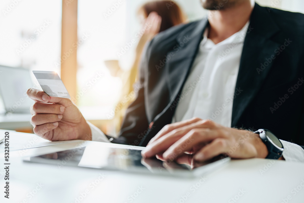 online payment and shopping, a male businessman uses a credit card to swipe for a discount using a tablet to select products online payment and shopping, a male businessman uses a credit card to swipe for a discount using a tablet to select products