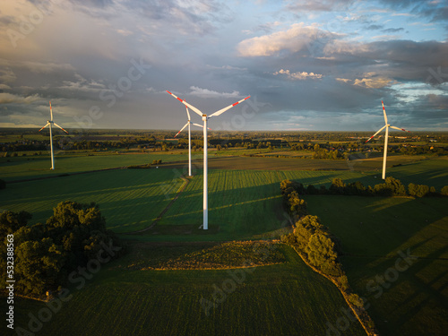 Aerial view of wind turbines under a cloud sky during sunset with long shadows