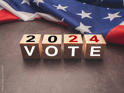 United States presidential election in 2024. Wooden cubes with text VOTE and 2024 over the American flag background
