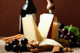 Fontal Italian pasteurized cow's milk cheese with black grapes and red wine on a rustic background.