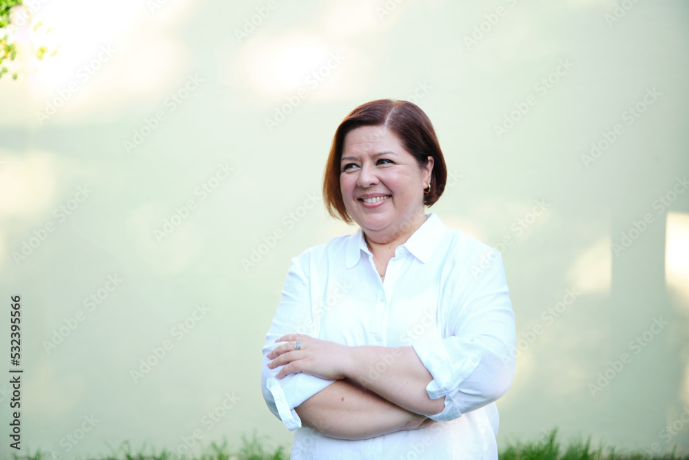 Smiling middle aged woman with short hair wearing white shirt with crossed arms Smiling middle aged woman with short hair wearing white shirt with crossed arms