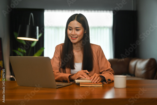 Pleased young businesswoman working, reading online Information on laptop computer