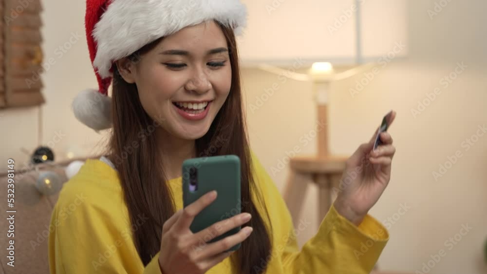 Young pretty asian girl using credit card and mobile buying product at home on christmas. Young pretty asian girl using credit card and mobile buying product at home on christmas.