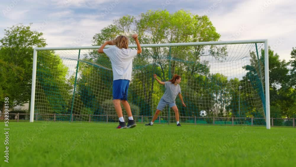 Slow motion shot of family playing soccer in park together. Happy parents and kids playing with ball in green meadow. Cheerful family enjoying summer outdoor activity Slow motion shot of family playing soccer in park together. Happy parents and kids playing with ball in green meadow. Cheerful family enjoying summer outdoor activity