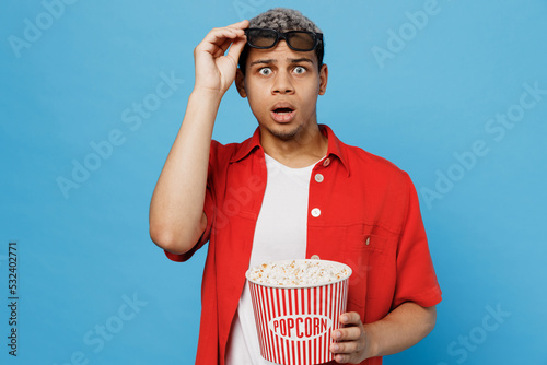 Φωτογραφία Young shocked surprised scared happy sad man of African American ethnicity lower 3d glasses watch movie film hold bucket of popcorn in cinema look camera isolated on yellow background studio portrait