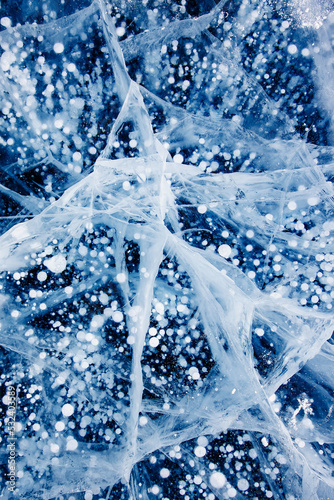 Gas methane bubbles frozen in winter ice of lake Baikal. Top view abstract background