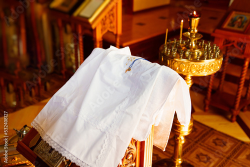 Fototapeta a white baptismal shirt and a cross on a table in the church during baptism