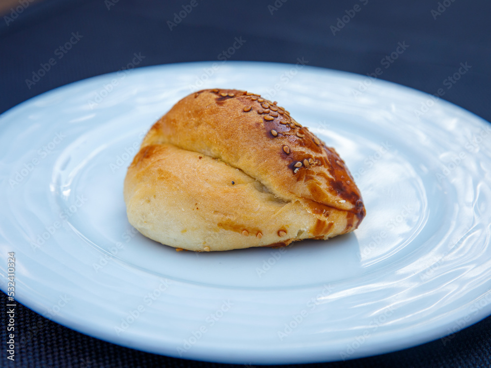 Traditional turkish bun pastry product , tasty pogaca with cheese filling on white plate close up Traditional turkish bun pastry product , tasty pogaca with cheese filling on white plate close up