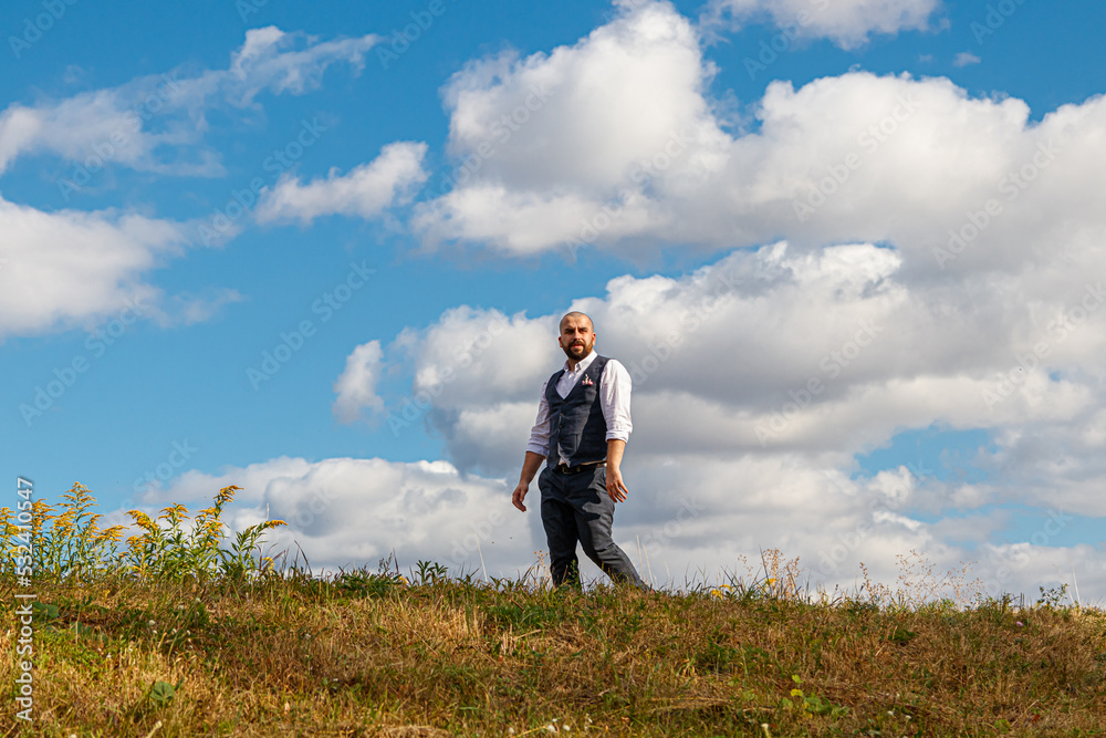 handsome guy in a suit among the field against the blue sky