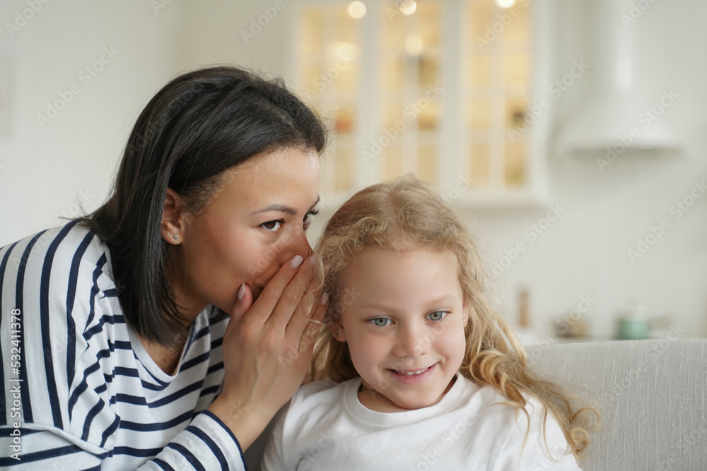 Mom or babysitter whisper secret to little elementary kid girl daughter. Family unity, child care Mom or babysitter whisper secret to little elementary kid girl daughter. Family unity, child care