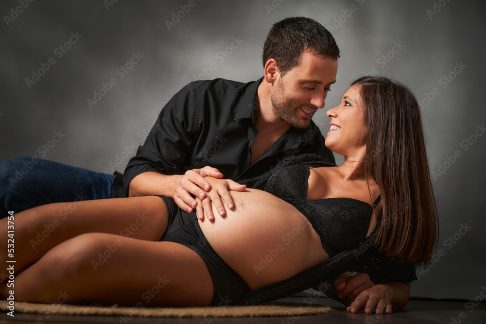 man and woman sitting on the floor touching the belly where their baby is growing man and woman sitting on the floor touching the belly where their baby is growing