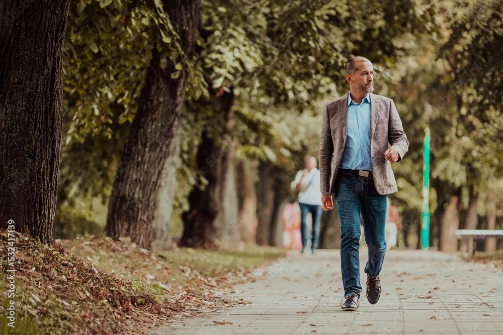 Fototapeta premium Focused businessman in a suit walking in the park