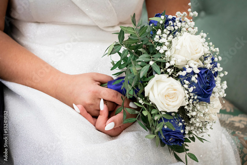 the bride's hands hold a bouquet with blue flowers