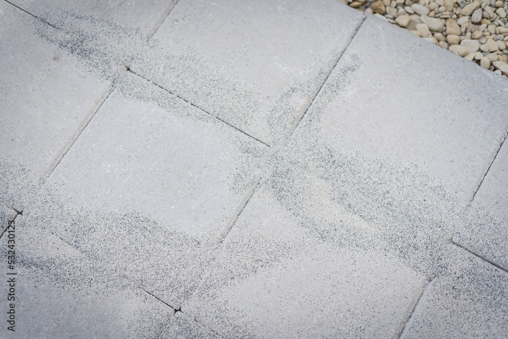 Polymeric paver sand on top of gray concrete patio stone paver brick