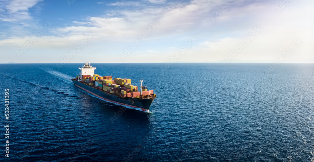 Panoramic aerial view of a cargo ship carrying containers for import and export, business logistic and transportation in open sea with copy space