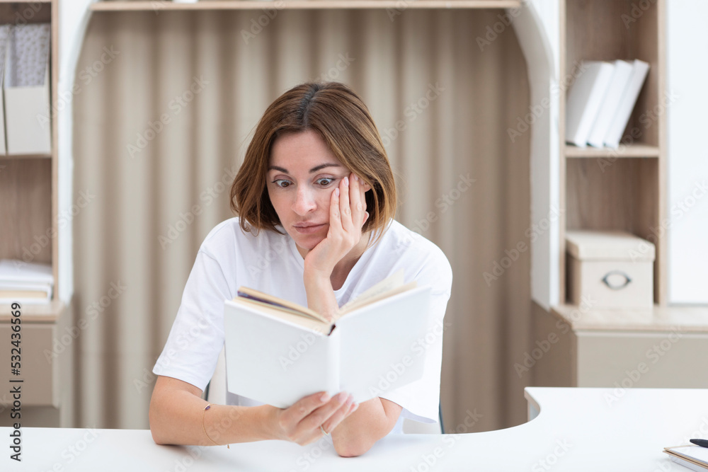 Young female student shocked after reading interesting chapter of book Young female student shocked after reading interesting chapter of book