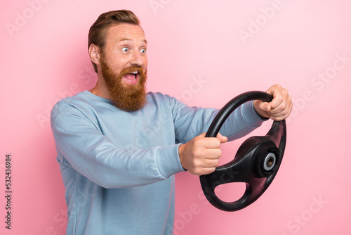 Photo of impressed ecstatic guy with ginger hairdo dressed blue sweater hold steering wheel test new car isolated on pink color background