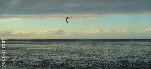 Kitesurfer im Watt der Nordsee bei Sonnenuntergang.