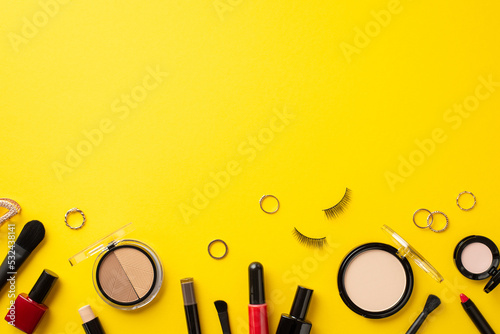 Black friday concept. Top view photo of cosmetics contouring palette nail polish false lashes powder eyeshadow lipstick brushes eyebrow marker gold rings on isolated yellow background with copyspace