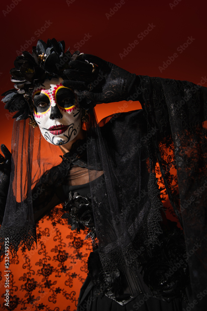 Woman in mexican santa muerte costume posing on red background. Woman in mexican santa muerte costume posing on red background.