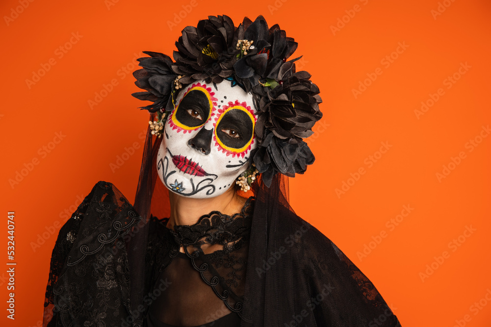 woman in creepy halloween makeup and wreath with black lace veil isolated on orange.