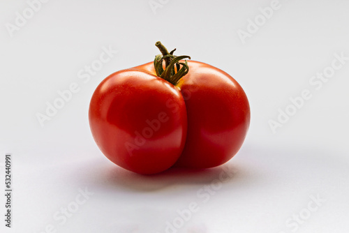 Wonky shaped and imperfect tomato in a suggestive shape, shot in a white studio.