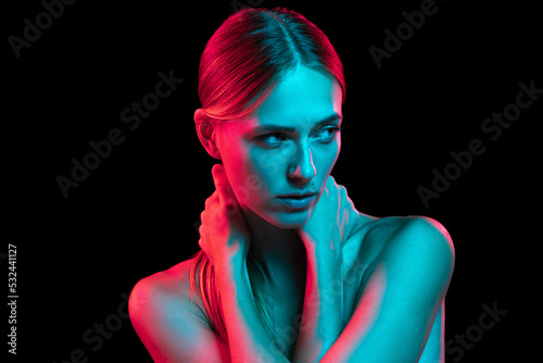 Young adorable woman with naked shoulders and well-kept skin in red neon light on dark background. Art, creativity, fashion, style