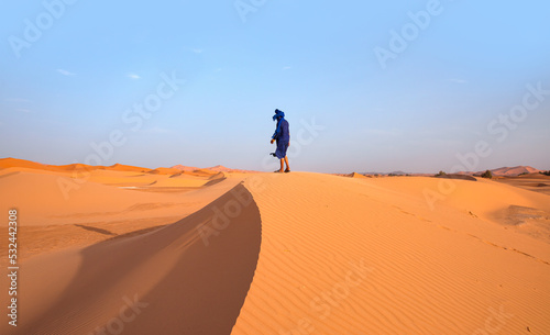 Happy bedouin in traditional bright clothing standing on sand in sahara desert - Sahara, Morocco