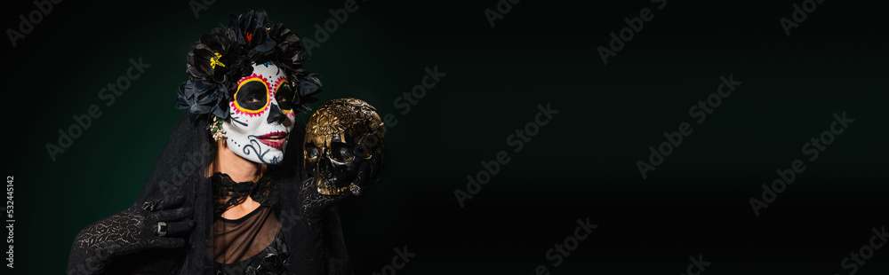 Woman in santa muerte costume holding skull on dark green background, banner.