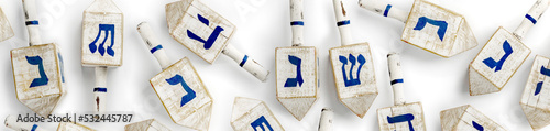 Dreidel also dreidle or dreidl with blue lettering on white background. Four-sided spinning top, played during the Jewish holiday of Hanukkah Jewish variant on the teetotum. Wooden gambling toy photo