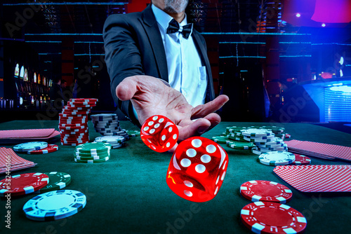 Gambling concept. Close up of male hand throwing dice at casino, gambling club. Сasino chips or Casino tokens, poker cards, gambling man spending time in games of chance
