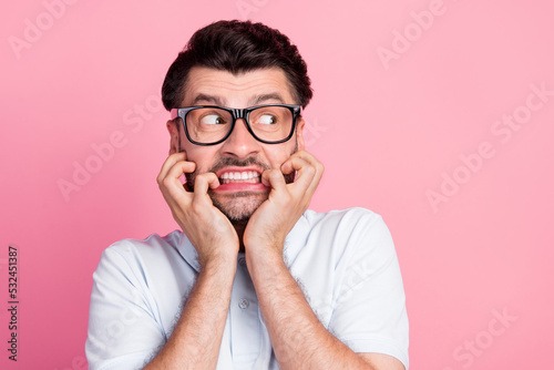 Closeup photo of young attractive handsome beard face nervous man wear white polo t-shirt bite nails look empty space ad isolated on pink color background